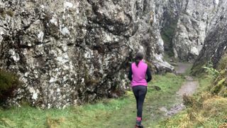 Woman hiking amongst rocks wearing purple vest