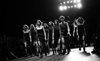 Many models walking on a runway wearing black