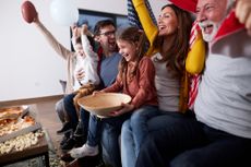 Cheerful extended family watching sports game on TV at home