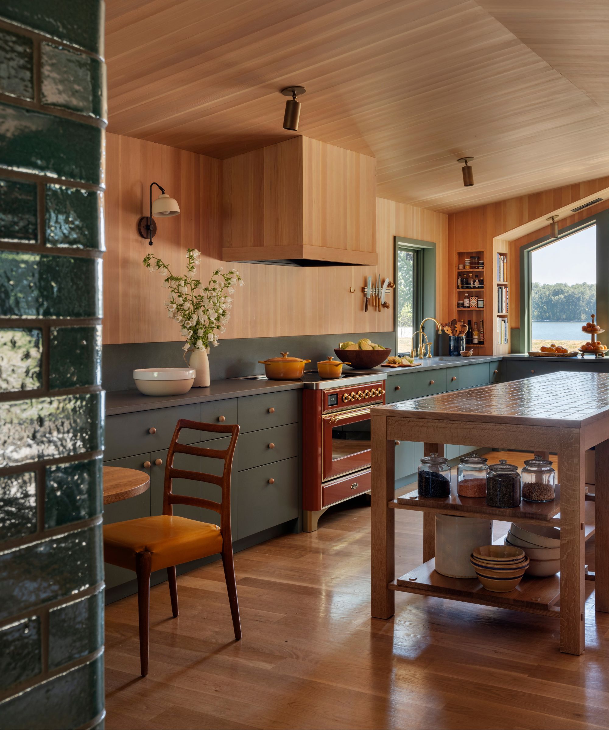 wood clad kitchen with green cabinetry and a red stove