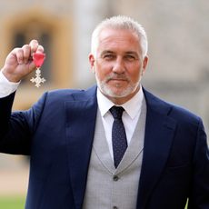  Paul Hollywood in navy suit after being made a Member of the Order of the British Empire. He is hold up his medal.