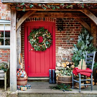 Red front door with Christmas wreath and decorations