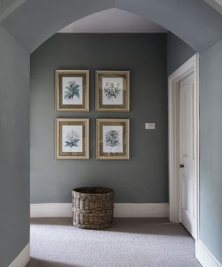 A hallway carpet idea with grey carpet, grey walls, white woodwork and gold framed art