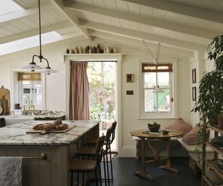 A shaker style kitchen with granite worktops on a kitchen island. There is a small built in seating area with a round table