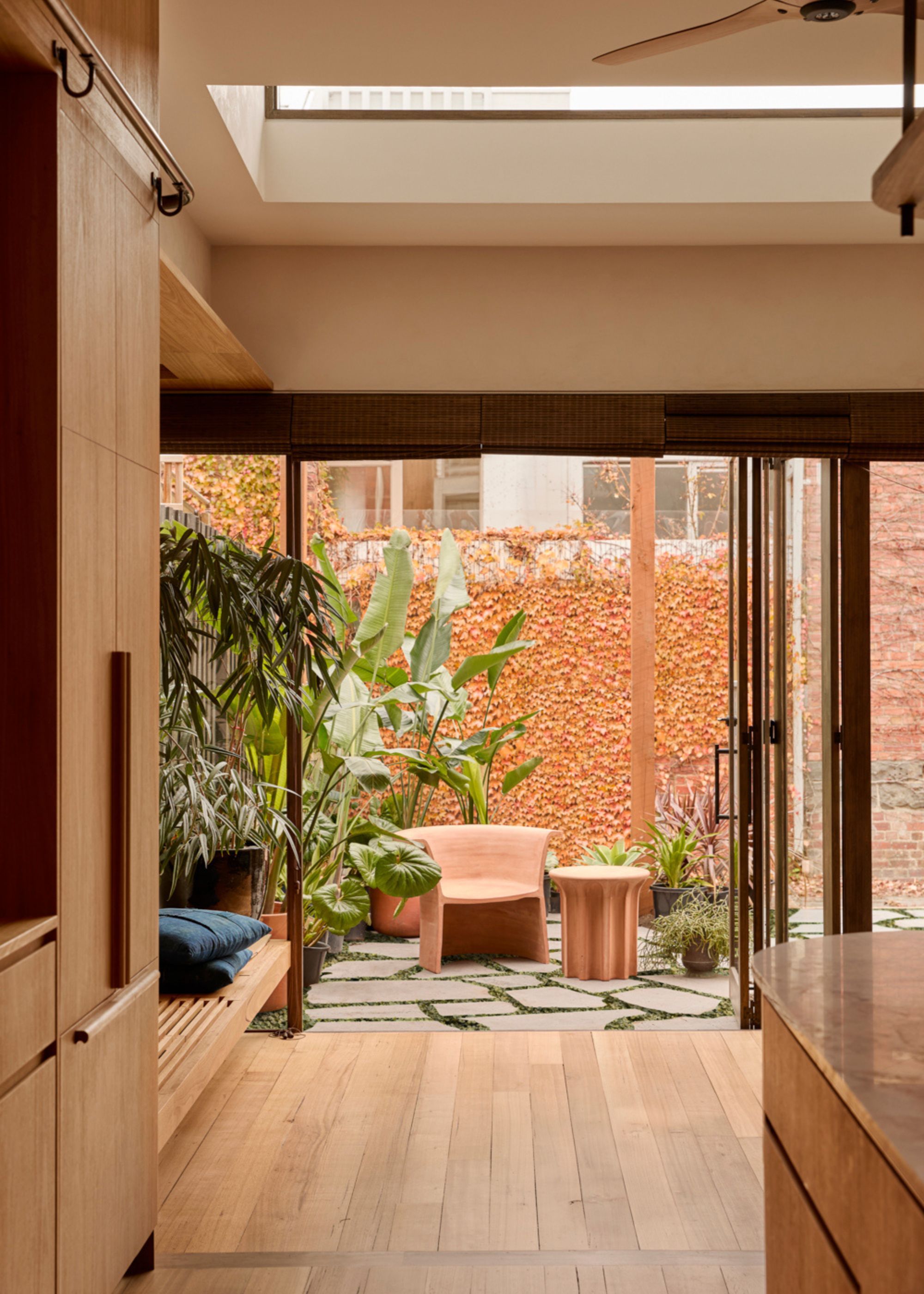 A kitchen leading to a small outdoor space with potted plants and a clay-colored seat and side table
