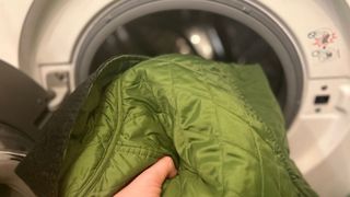 A quilted Barbour jacket being put into a washing machine