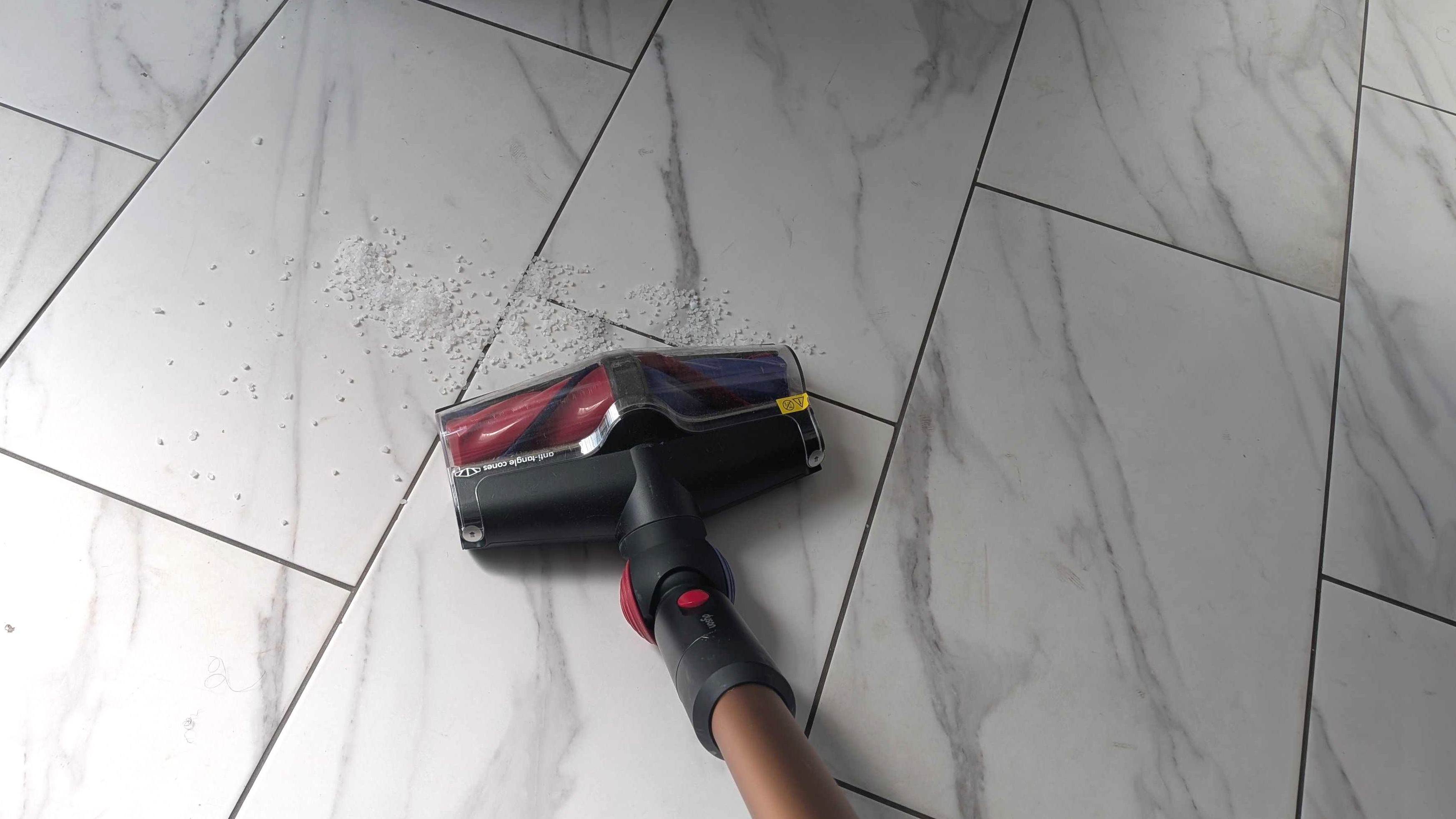 Dyson V16 Animal Piston cleaning debris on the whilte floor tiles