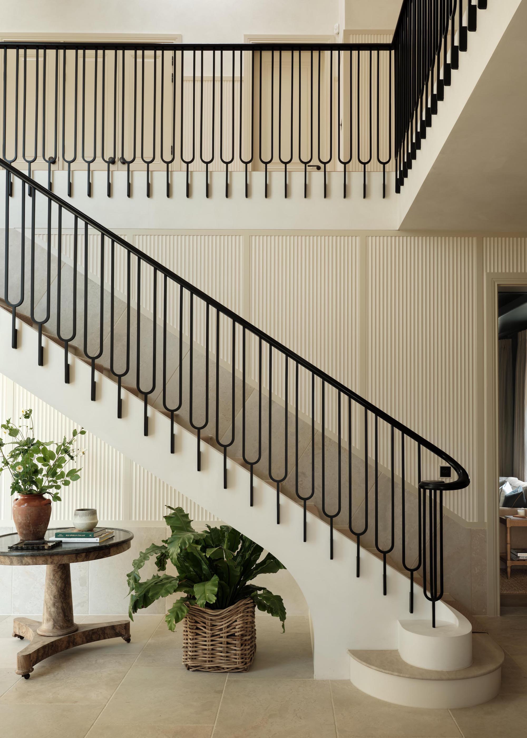 staircase with black metal banisters and limestone treads