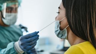 medical worker in protective clothing giving a nose swab to a female patient