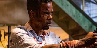 Chris Rock bloody and holding a gun in Spiral: From The Book Of Saw