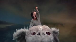 Barret Oliver flying high on Falcor, with his fist raised in the air in The NeverEnding Story.