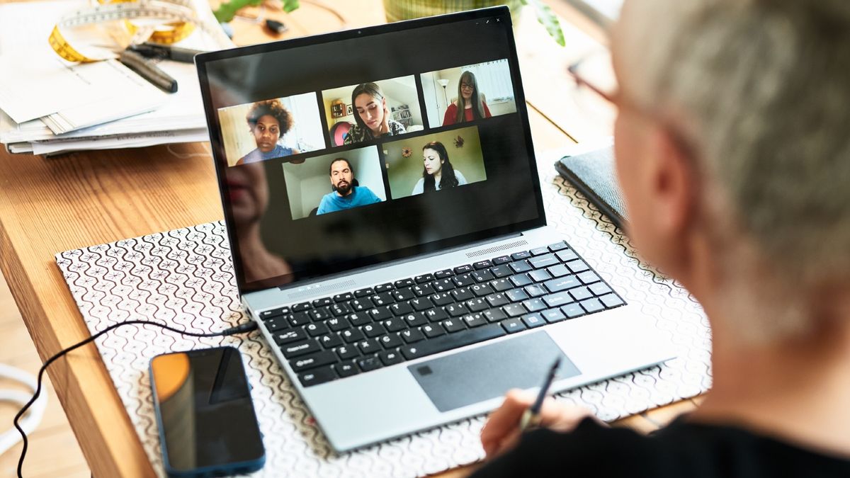 A woman looks at a video call meeting on a laptop screen