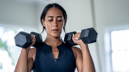 Woman holding two dumbbells above her shoulders