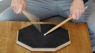 Man practices drum rolls on a pad
