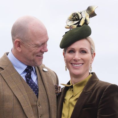 Mike Tindall in a brown suit smiling at Zara Tindall, dressed in a green suit and hat