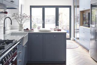 A grey L shaped kitchen with windows facing a garden