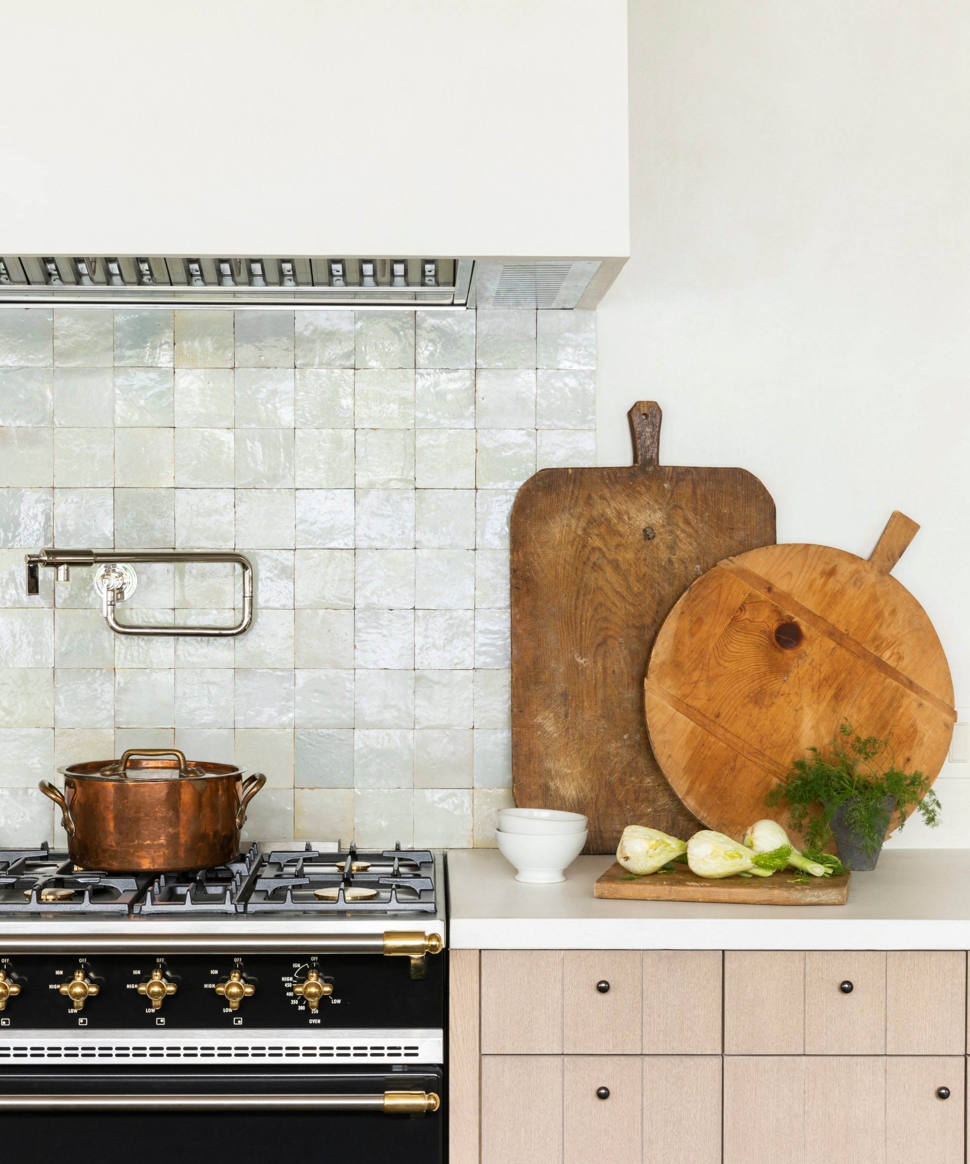 the range area of a neutral kitchen with a glossy square white tile backsplash