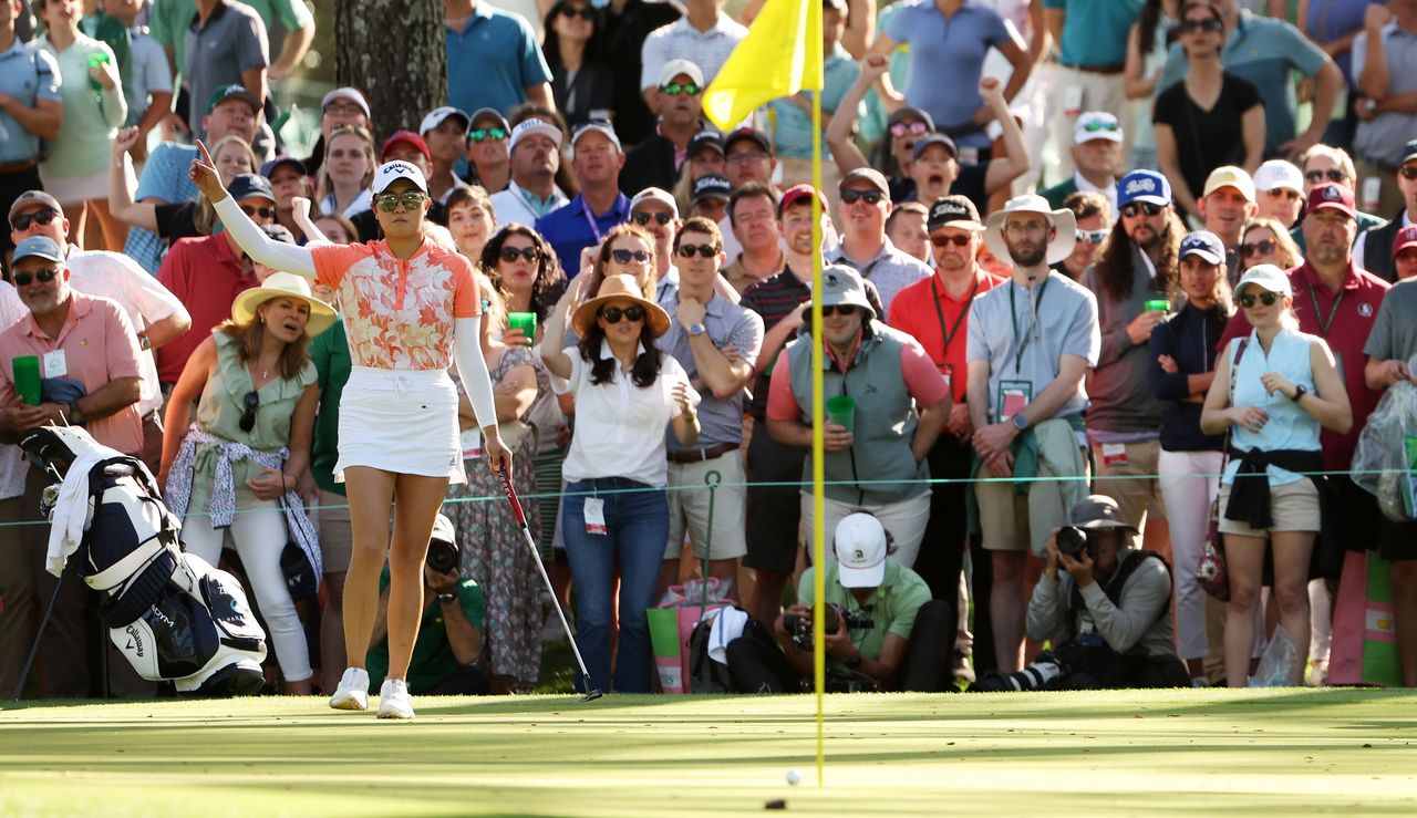 Zhang lifts her hand in the air whilst her putt rolls towards the hole