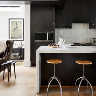 Black and white kitchen with wooden stools and artwork on wall