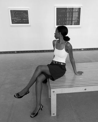 Fashion influencer Sylvie Mus wearing a tank top, tailored shorts, and slingbacks at an art museum.