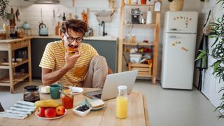 Man eating at table while working