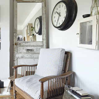 armchair with white walls clock on wall and wooden flooring