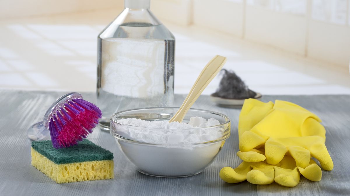 Baking soda white vinegar and washing up gloves on a kitchen worktop