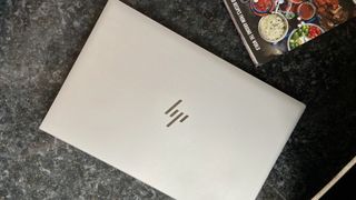 The lid of the HP EliteBook 840 G7 with HP logo and cookbook in background