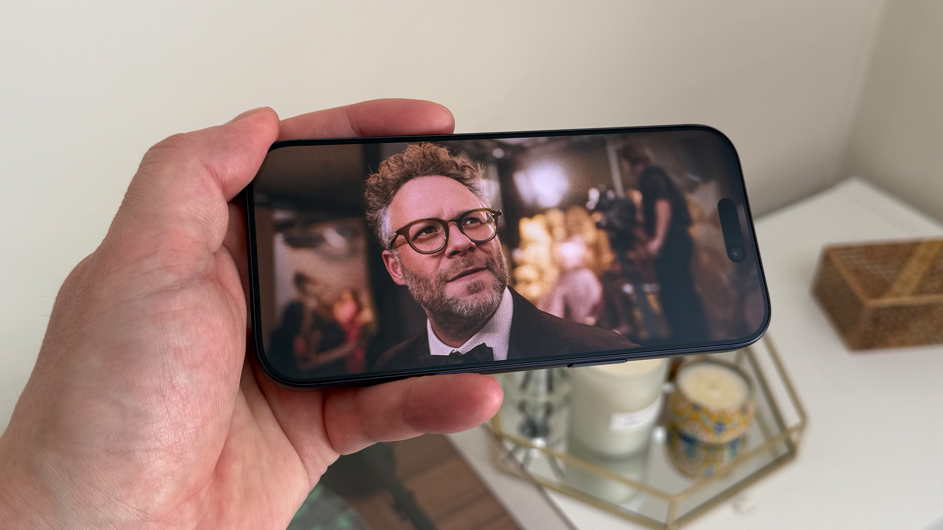 Apple iPhone 17 Pro smartphone held in hand, on screen is Seth Rogen