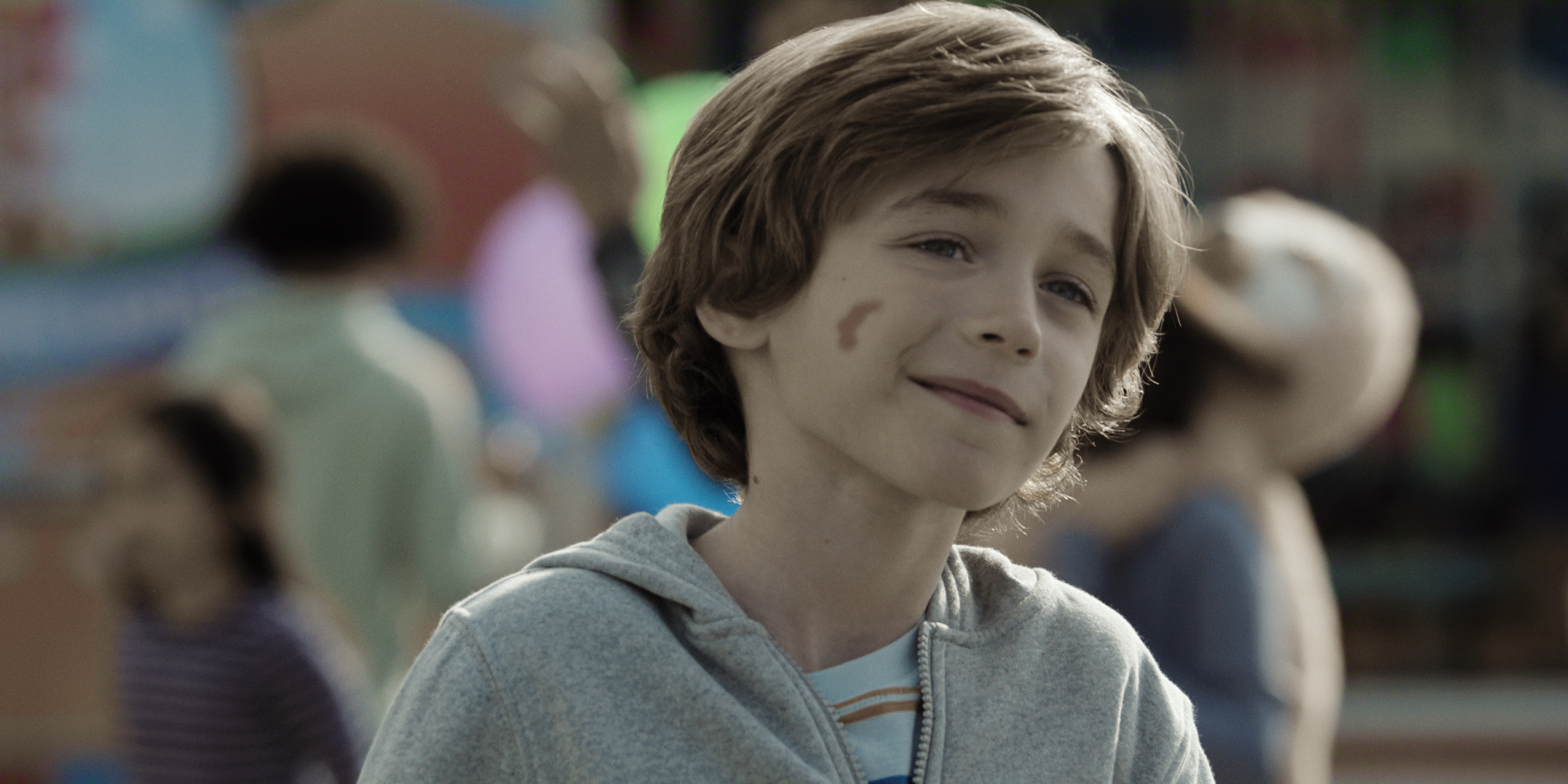 Ashton Cressman as matthew smiling in a crowd of children in a still from I Will Find You