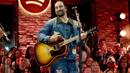 Noah Kahan performing on stage with a guitar