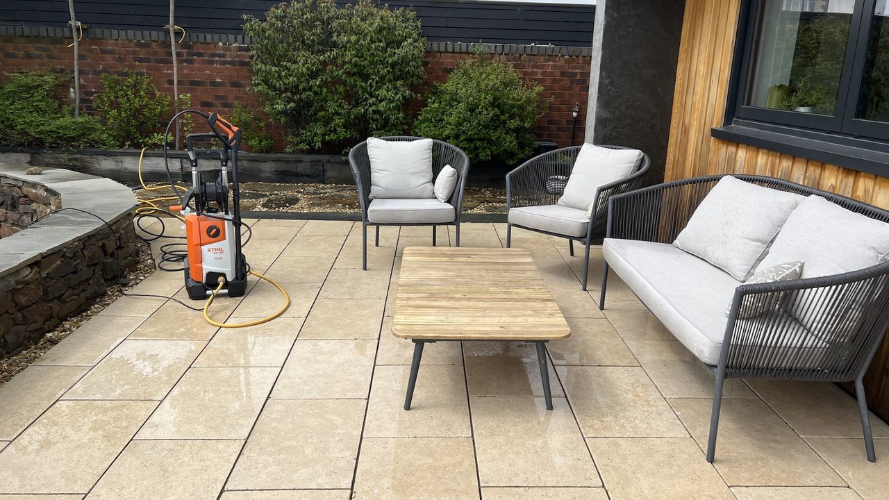 pressure washer on wet patio with garden chairs and table