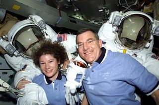 Astronauts James S. Voss and Susan J. Helms, STS-102 mission specialists, are pictured with their Extravehicular Mobility Unit (EMU) space suits on the mid deck.