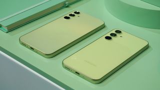 Samsung Galaxy A54 och A34 i grönt ligger med baksidorna vända uppåt på ett matchande grönt bord, sett snett från sidan.