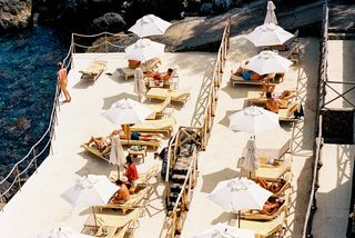 People lounging in the sun, next to the sea, in Italy