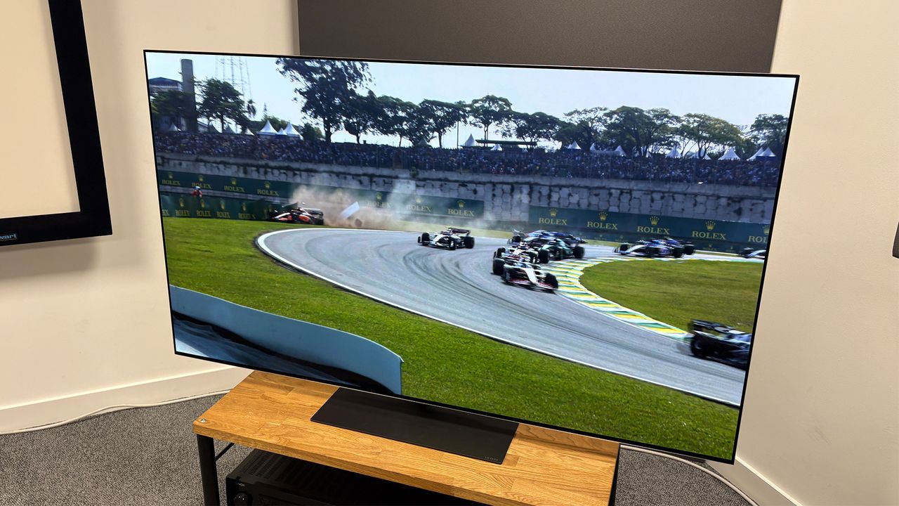 The 65-inch LG G5 OLED TV pictured on a wooden rack. On the screen is a still from Netflix F1 series Drive to Survive.