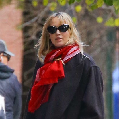 Jennifer Lawrence wearing a black coat and red scarf