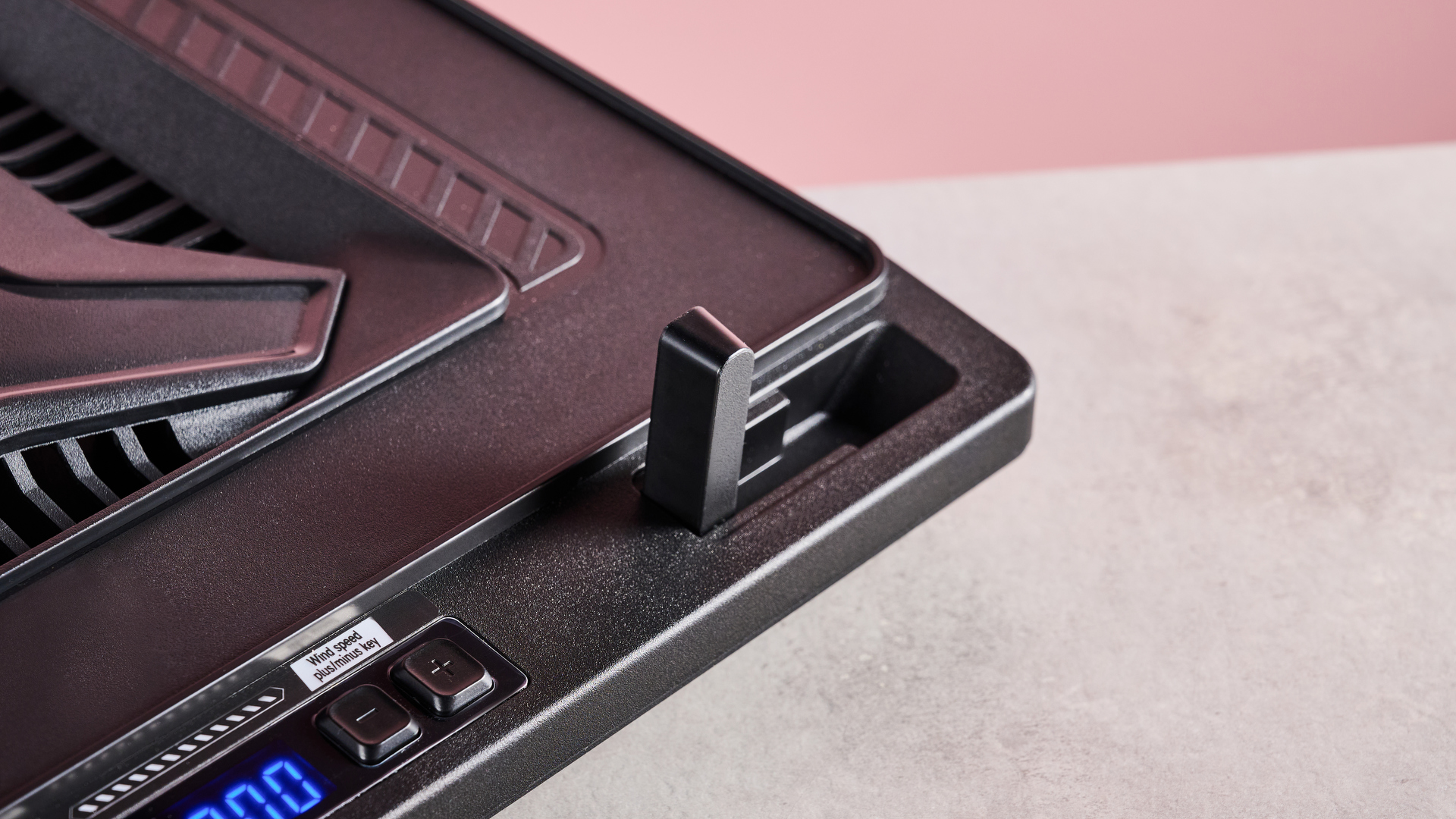 A closeup of the bottom-right corner of the Llano V10 Gaming Laptop Cooling Pad in front of a pink background.