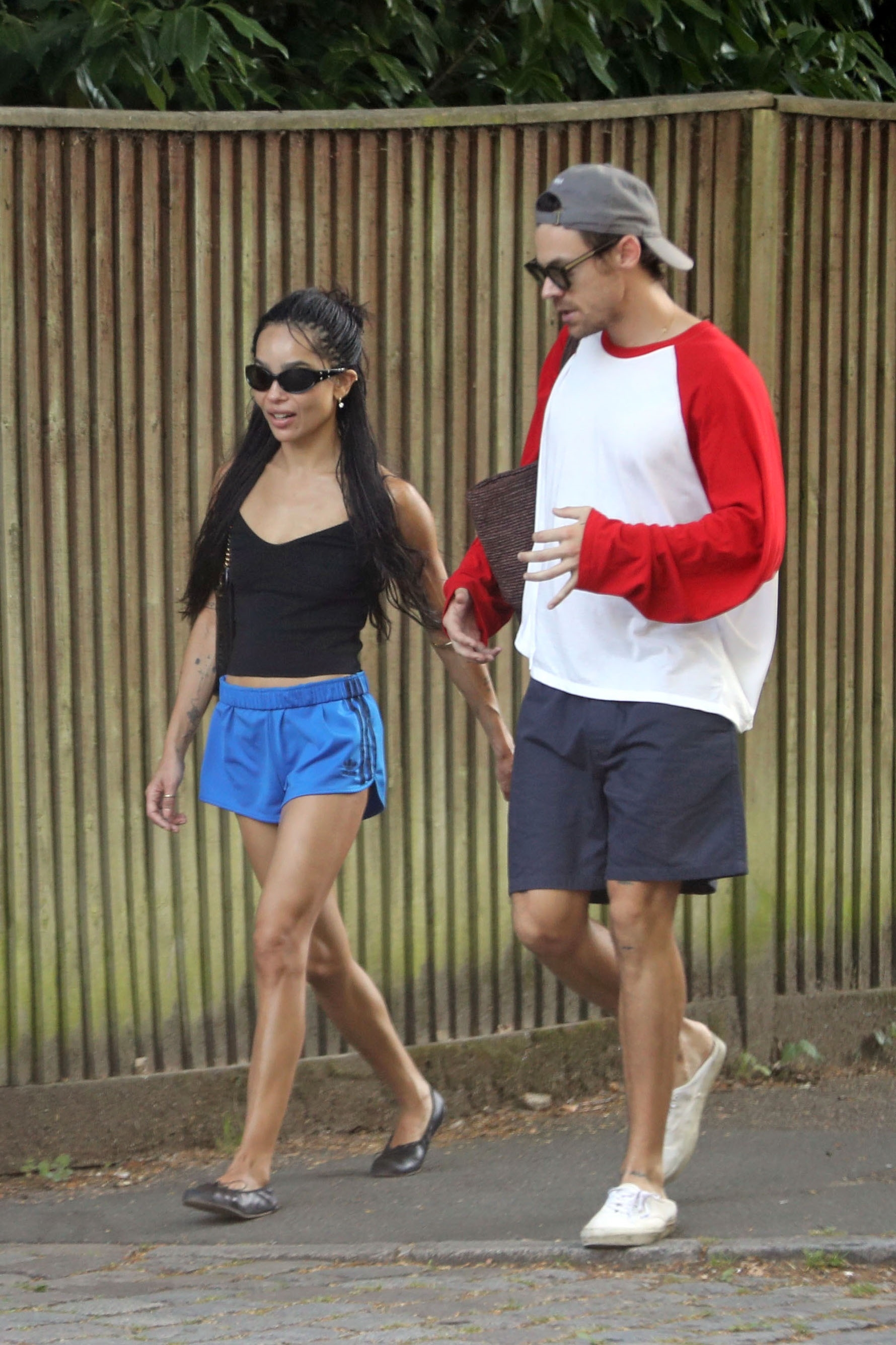 Zoe Kravitz in a black top and blue track shorts; Harry Styles in a baseball tee and shorts