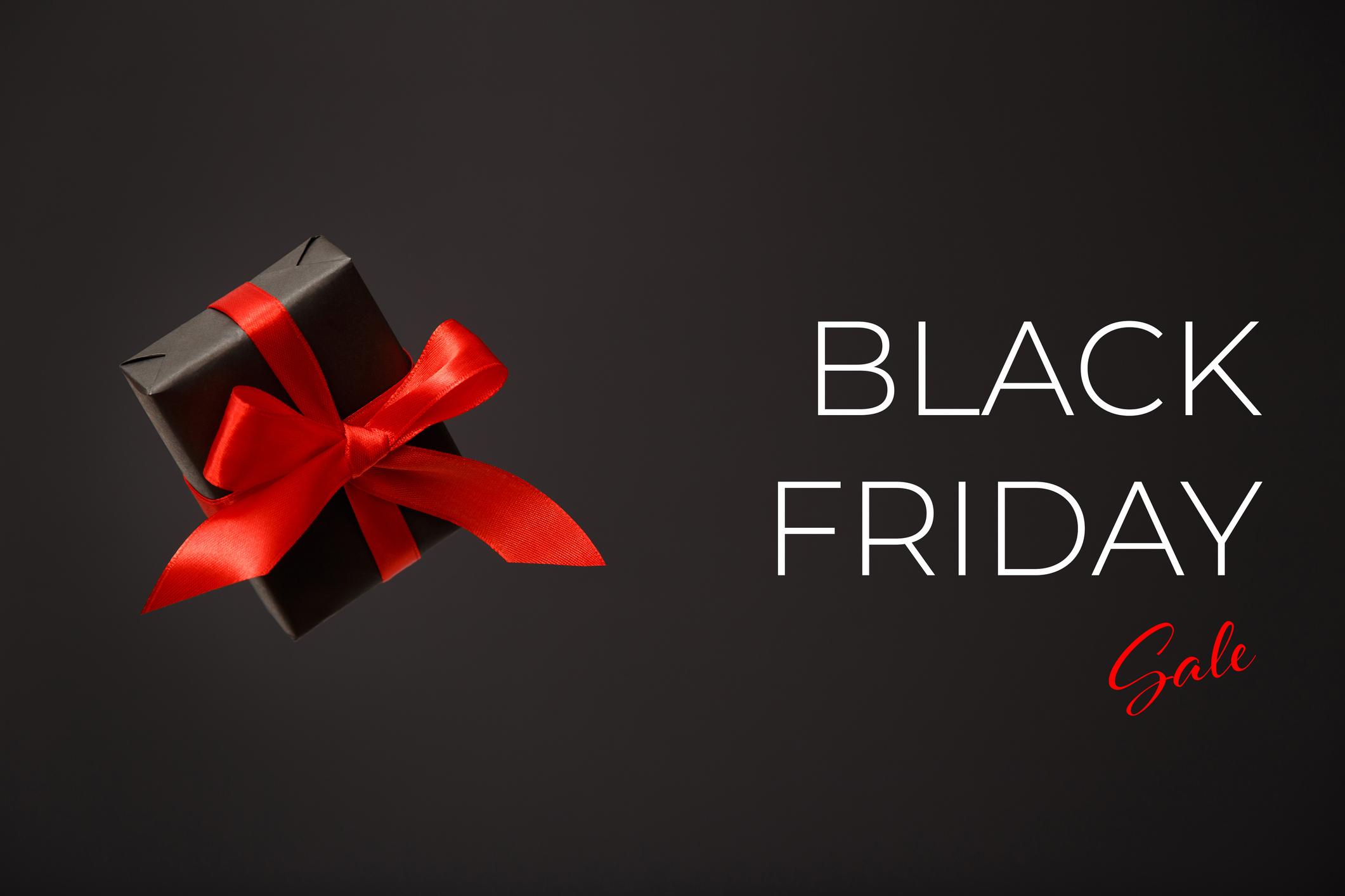  Black Friday sale. Black gift box with red bow floating in air on black background. Discount, online shopping concept 