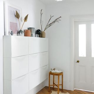 white hallways with wall storage and small stool