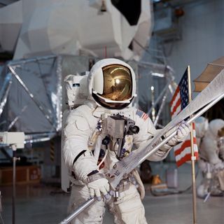Apollo 13 lunar module pilot Fred Haise completes lunar surface training exercises inside the Kennedy Space Center while preparing for extravehicular activities on the moon. Haise is wearing an Extravehicular Mobility Unit as he carries the Solar Wind Composition Experiment, which consists of an aluminum foil sheet deployed on a pole facing the sun.