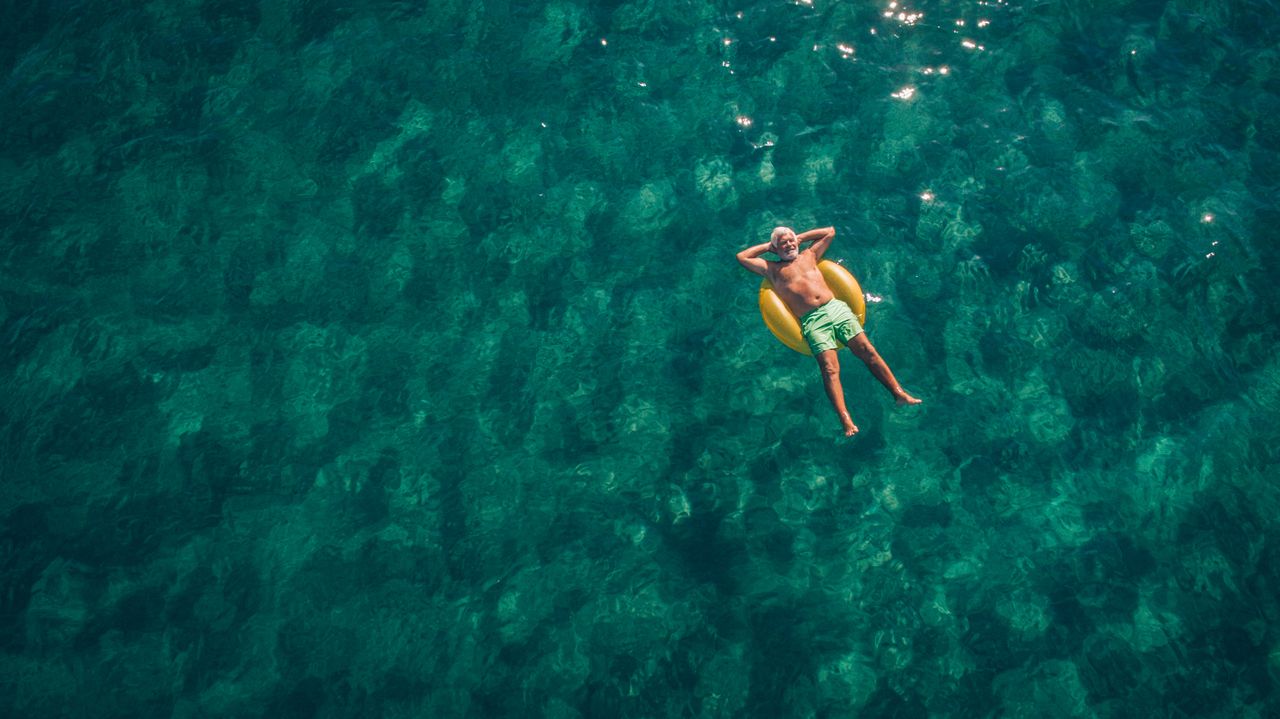 Retirement symbolised by a man floating in a crystal clear sea