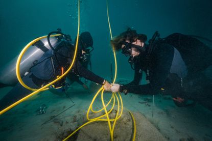 Scuba Divers Installing undersea cables for research purposes