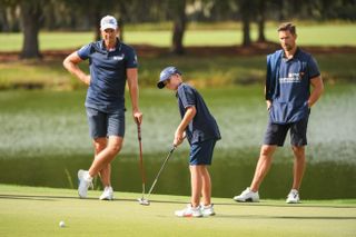 Karl Stenson hits a putt in front of his dad and caddie