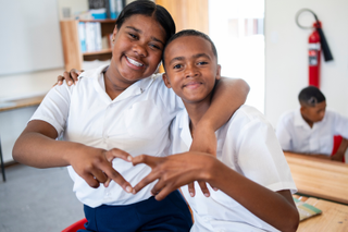 a girl and boy at school making a heart shape with their fingers