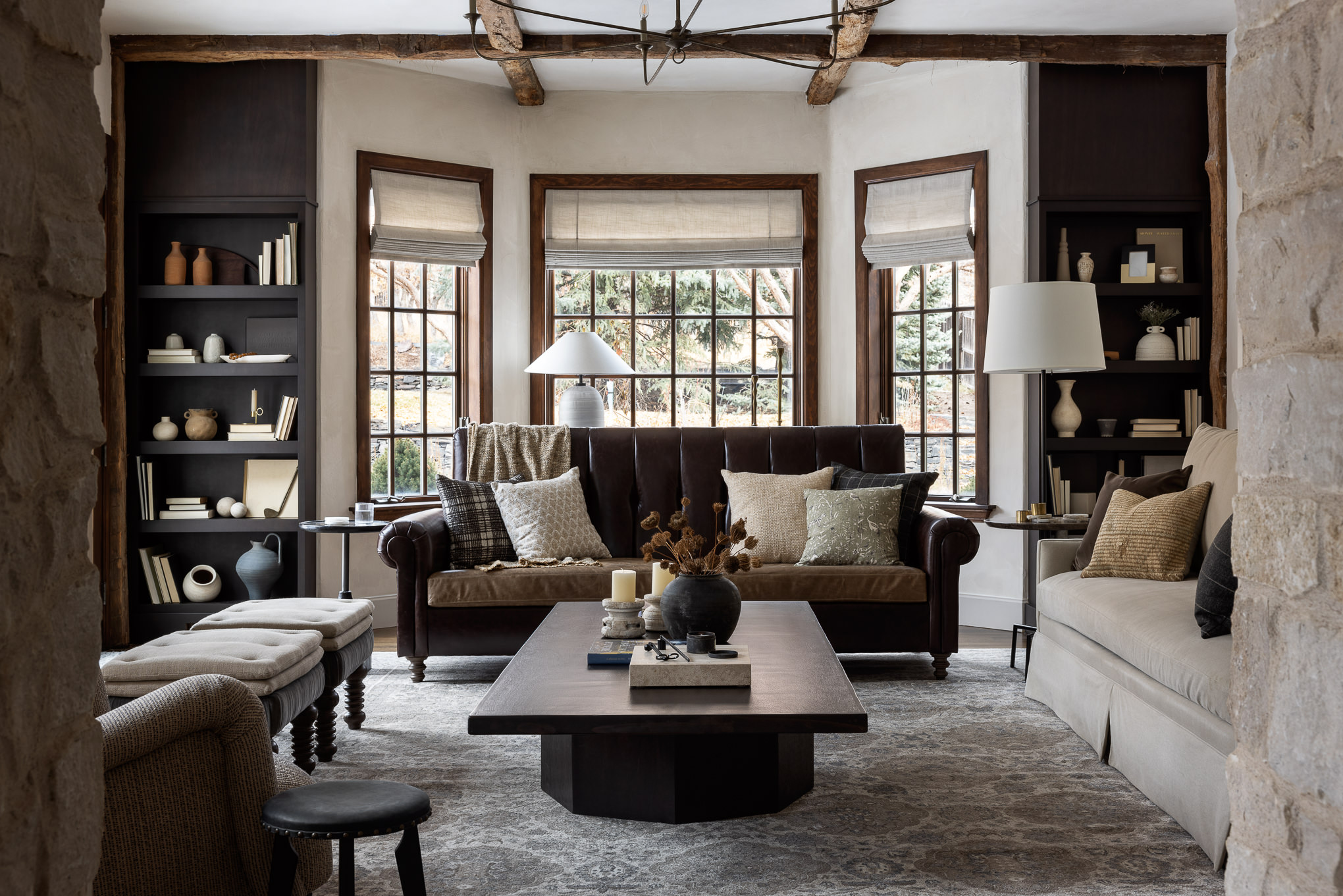 A well-designed living room with a traditional spin. A leather sofa in front of bay windows.