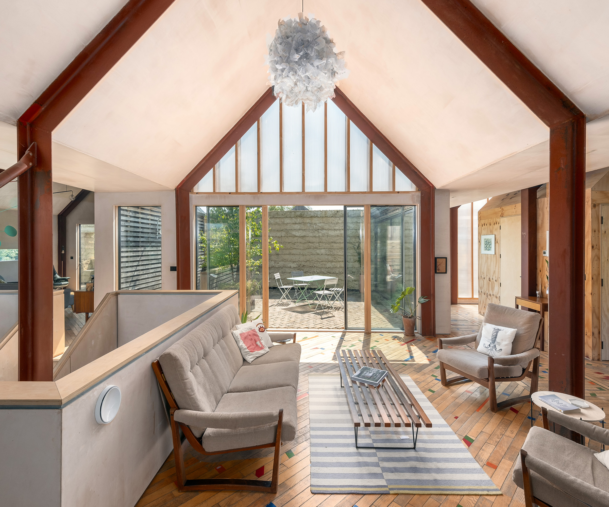 Exposed beams in a pitched ceiling of a self build home. There is an open plan living space with midcentury furniture and plenty of natural light