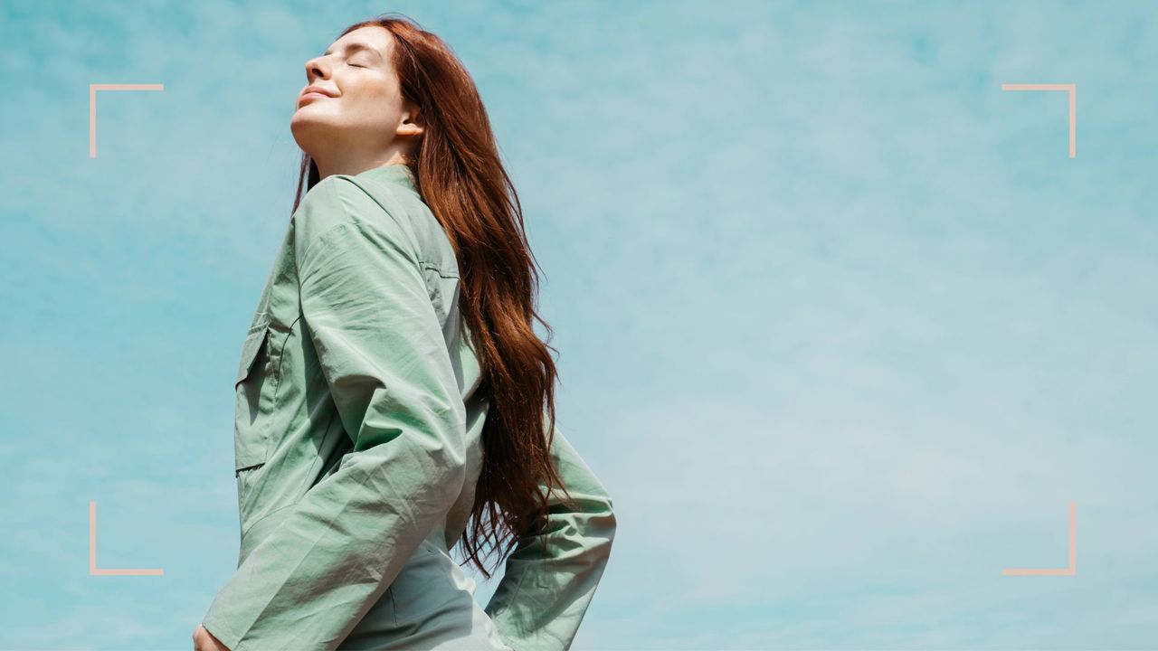 A woman with very long red hair standing in the sun, to demonstrate the benefits of biotin for hair growth