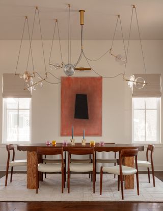 A bright dining room with wired hanging light fixtures and colorful glassware